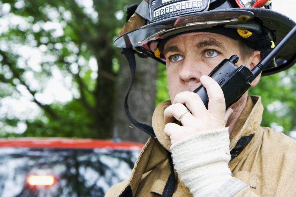 A firefighter uses a radio.